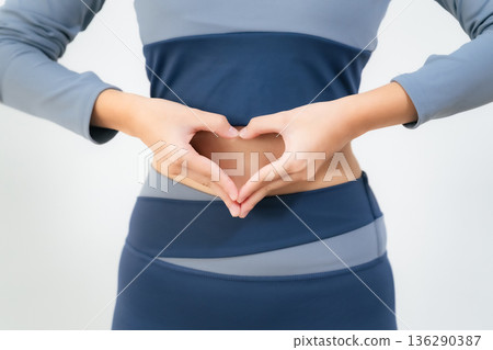 A woman making a heart symbol on her stomach A woman making a heart symbol on her stomach 136290387