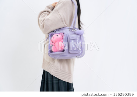 A female student carrying a bag containing a stuffed toy 136290399