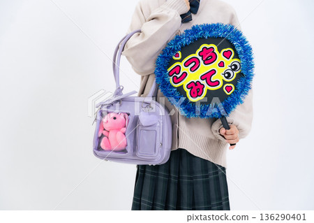 一名女學生手提一個裝有扇子和毛絨玩具的包包。 136290401