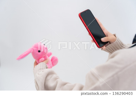 A female student taking a photo of a stuffed animal with her smartphone 136290403