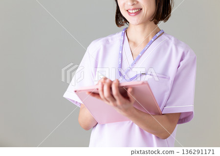 A middle-aged female nurse in a medical scrub 136291171