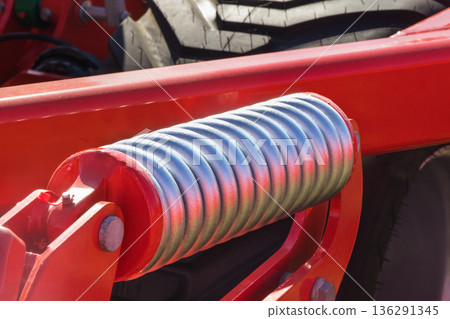 Steel silver spring as part of red heavy agricultural, industrial machine. Technology Steel silver spring as part of red heavy agricultural, industrial machine. Technology 136291345