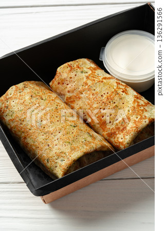 Burritos served in a black box with dipping sauce on a white table 136291566