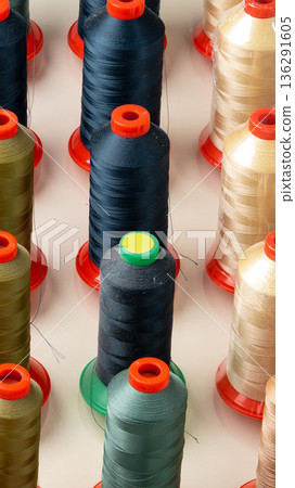 Rows of thread spools in various colors on a flat surface in a crafting area Rows of thread spools in various colors on a flat surface in a crafting area 136291605