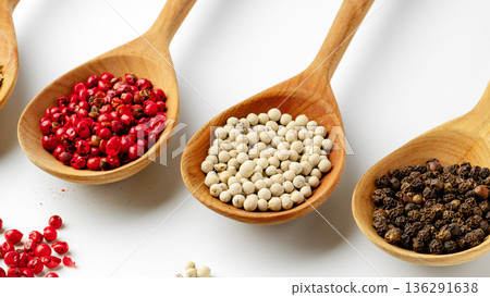 Different types of pepper shown in wooden spoons on a white background 136291638