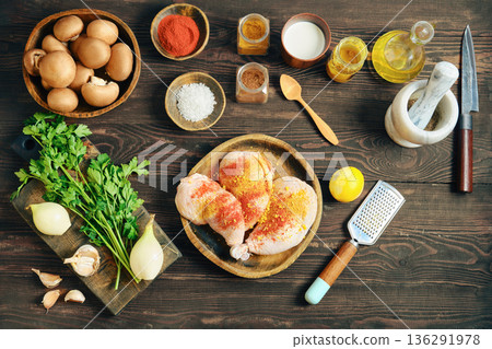 Top view of seasoned chicken leg with fresh ingredient and spice on dark rustic wood background 136291978