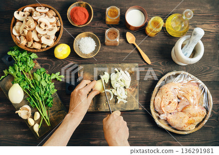 Top view of hands slicing fresh white onion on a wooden cutting board Top view of hands slicing fresh white onion on a wooden cutting board 136291981