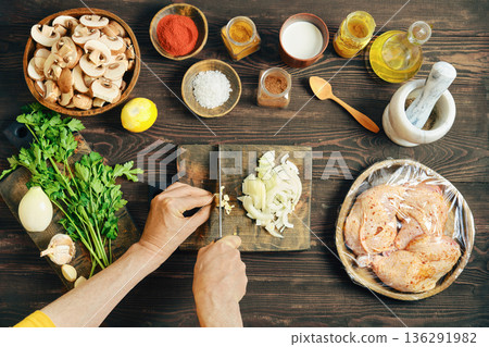 Top view of hands chopping fresh garlic on a wooden cutting board Top view of hands chopping fresh garlic on a wooden cutting board 136291982