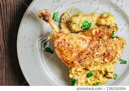 Chicken dish served on a plate with herbs and a creamy sauce at a dining table 136292004
