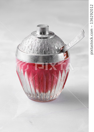 Decorative bowl with red lingonberry jam and silver lid placed on a white surface in a kitchen setting Decorative bowl with red lingonberry jam and silver lid placed on a white surface in a kitchen setting 136292012