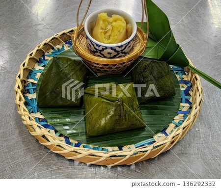 Traditional Thai Steamed Desserts Wrapped in Banana Leaves on Woven Tray Traditional Thai Steamed Desserts Wrapped in Banana Leaves on Woven Tray 136292332