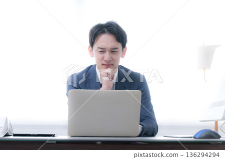 一幅畫面描繪了一位總裁或經理正憂心忡忡地看著一張業務策略和業績圖表，他手托著下巴，顯得猶豫不決。 136294294