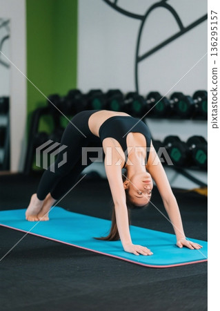 女性健身房内做瑜伽动作 女性健身房内做瑜伽动作 136295157
