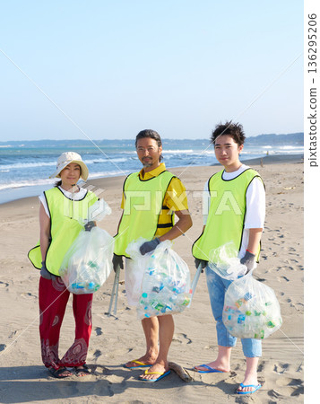 A group of volunteers looking at the camera with bags of trash collected during a beach cleanup A group of volunteers looking at the camera with bags of trash collected during a beach cleanup 136295206