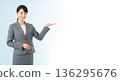 A smiling businesswoman in a suit giving directions. A versatile advertising image with ample white space on the right. 136295676