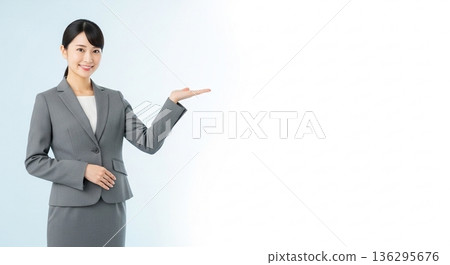 A smiling businesswoman in a suit giving directions. A versatile advertising image with ample white space on the right. A smiling businesswoman in a suit giving directions. A versatile advertising image with ample white space on the right. 136295676