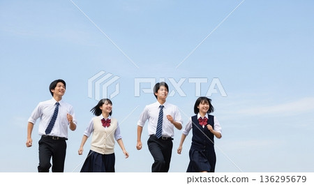 Four high school students, boys and girls, running with smiles under the blue sky. Refreshing advertising material with the image of youth, the future, education, and starting a new life. Four high school students, boys and girls, running with smiles under the blue sky. Refreshing advertising material with the image of youth, the future, education, and starting a new life. 136295679