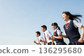 Four high school boys and girls running with smiles under the blue sky. With a wide margin on the left, this advertising material evokes the image of youth and the future. 136295680