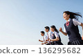 Four high school students, two boys and two girls, running with smiles under the blue sky. With a wide margin on the left, this advertising material evokes the image of youth and the future. 136295682
