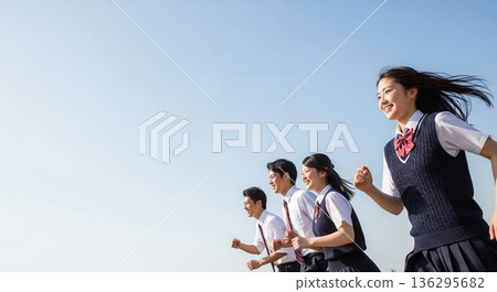 Four high school students, two boys and two girls, running with smiles under the blue sky. With a wide margin on the left, this advertising material evokes the image of youth and the future. 136295682