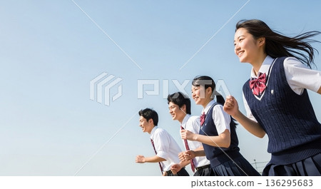Smiling high school boys and girls running under the blue sky. With a wide margin on the left, this refreshing advertising material evokes images of youth and the future. Smiling high school boys and girls running under the blue sky. With a wide margin on the left, this refreshing advertising material evokes images of youth and the future. 136295683