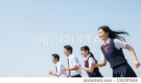 Four high school boys and girls running with smiles under the blue sky. With a wide margin on the left, this advertising material evokes the image of youth and the future. Four high school boys and girls running with smiles under the blue sky. With a wide margin on the left, this advertising material evokes the image of youth and the future. 136295684