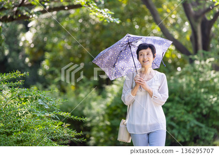一位面帶微笑的中年婦女撐著陽傘 一位面帶微笑的中年婦女撐著陽傘 136295707