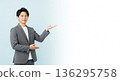A smiling male business person in a suit giving directions. A versatile advertising image with ample white space on the right. 136295758