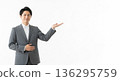 A smiling male business person in a suit giving directions. A versatile advertising image with ample white space on the right. 136295759