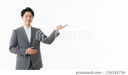 A smiling male business person in a suit giving directions. A versatile advertising image with ample white space on the right. A smiling male business person in a suit giving directions. A versatile advertising image with ample white space on the right. 136295759