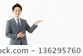 A smiling male business person in a suit giving directions. A versatile advertising image with ample white space on the right. 136295760
