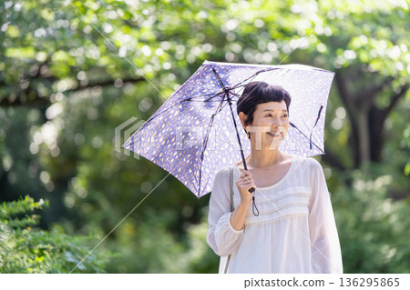 一位面帶微笑的中年婦女撐著陽傘 一位面帶微笑的中年婦女撐著陽傘 136295865