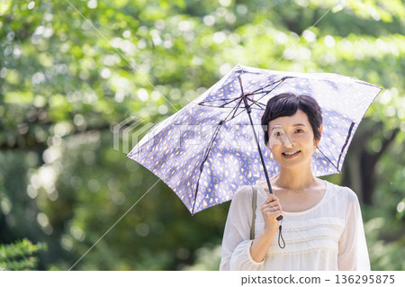 一位面帶微笑的中年婦女撐著陽傘 一位面帶微笑的中年婦女撐著陽傘 136295875