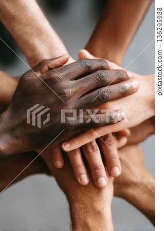 A close-up of multiple diverse hands stacked on top of each other, symbolizing unity, support, and strength within a cohesive team. 136295988