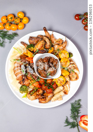 Top view of chicken platter with vegetables and sauce on white plate 136296053