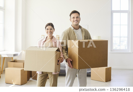 Happy proud couple holding cardboard boxes to move into new home apartment Happy proud couple holding cardboard boxes to move into new home apartment 136296418