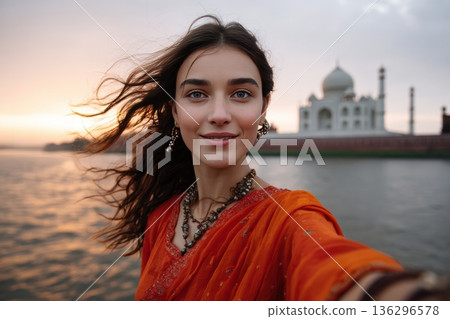 Woman in sari takes selfie with taj mahal at sunset, wearing traditional jewelry and vivid clothing Woman in sari takes selfie with taj mahal at sunset, wearing traditional jewelry and vivid clothing 136296578
