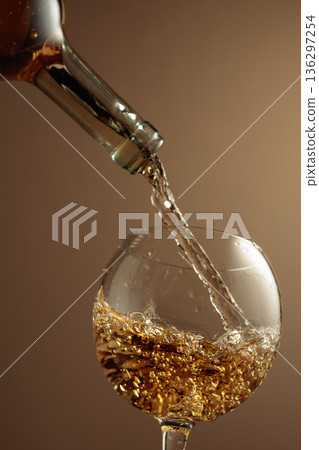 Pouring white wine from a bottle into a glass. 136297254