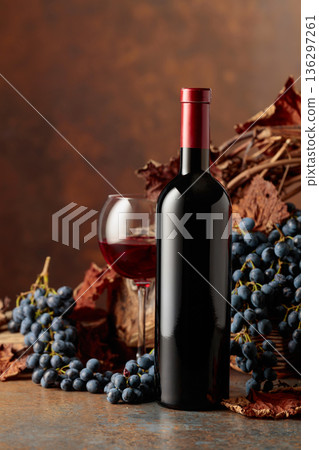 Bottle of red wine with blue grapes on a brown background. Bottle of red wine with blue grapes on a brown background. 136297261