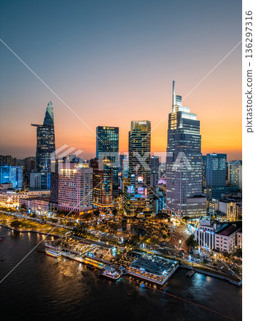 night view of illuminated Ho Chi Minh city skyline and Saigon river, neon street lights of financial downtown district with tall skyscraper towers, Vietnam aerial drone view 136297316
