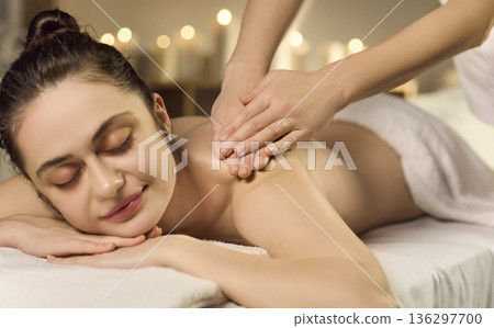 Peaceful spa massage therapy on female client with candlelight and soothing care 136297700