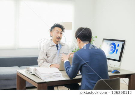 工程師們在辦公室一邊開會一邊查看文件。 136298113