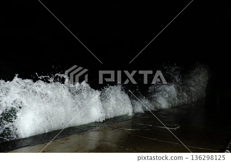 A powerful wave crashes, spraying white foam against darkness. A powerful wave crashes, spraying white foam against darkness. 136298125