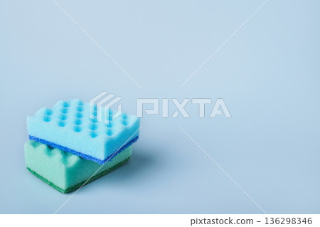 Two colorful cleaning sponges are stacked on light blue background with copy space Two colorful cleaning sponges are stacked on light blue background with copy space 136298346