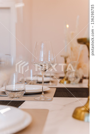 Elegant restaurant table setting with glassware, pampas decor and warm bokeh lighting Elegant restaurant table setting with glassware, pampas decor and warm bokeh lighting 136298785