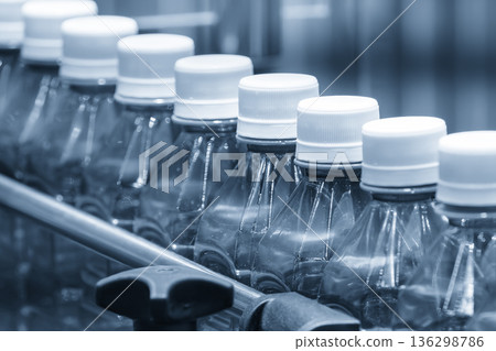 Plastic Bottle Filling Process on Conveyor Belt in Blue Tone Automated Manufacturing Line Plastic Bottle Filling Process on Conveyor Belt in Blue Tone Automated Manufacturing Line 136298786