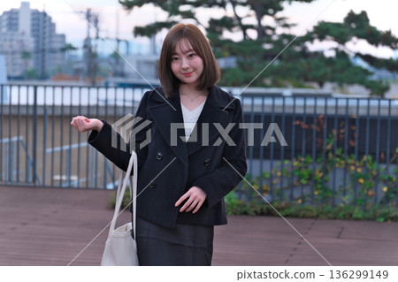 A female university student (Japanese woman) in winter clothes standing on the rooftop with her bag. An image of commuting to school, going out, and starting a new life. A female university student (Japanese woman) in winter clothes standing on the rooftop with her bag. An image of commuting to school, going out, and starting a new life. 136299149