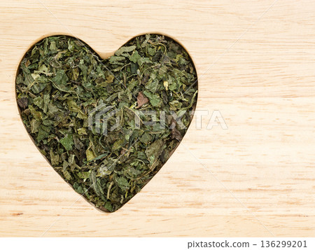 Dried nettle leaves heart shaped on wooden surface Dried nettle leaves heart shaped on wooden surface 136299201