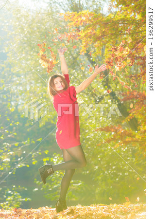 Young woman tossing leaves. Young woman tossing leaves. 136299517