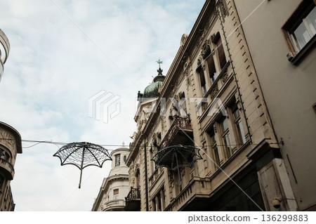 Historic buildings in Belgrade old town with decorative umbrellas hanging above the street, combining classic European architecture and creative urban street decoration Historic buildings in Belgrade old town with decorative umbrellas hanging above the street, combining classic European architecture and creative urban street decoration 136299883